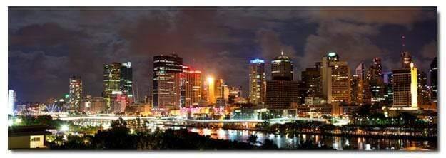 Stretched canvas wall art of a cloudy Brisbane skyline at night, showcasing vibrant city lights and reflections.